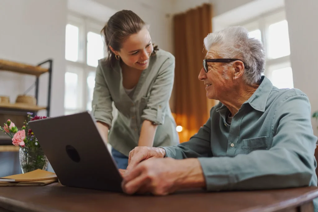 Support worker helping elderly man with technology at home