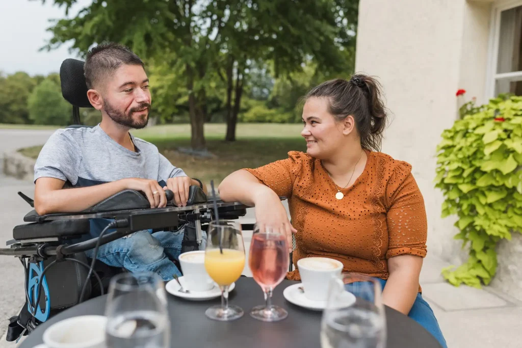 Man in wheelchair enjoying coffee with companion outdoors