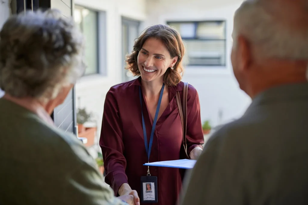 Support worker greeting elderly couple at home