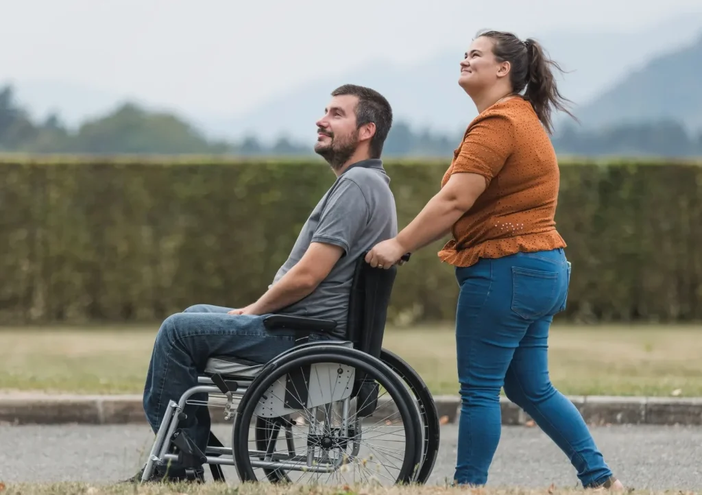Support worker pushing client in wheelchair outdoors