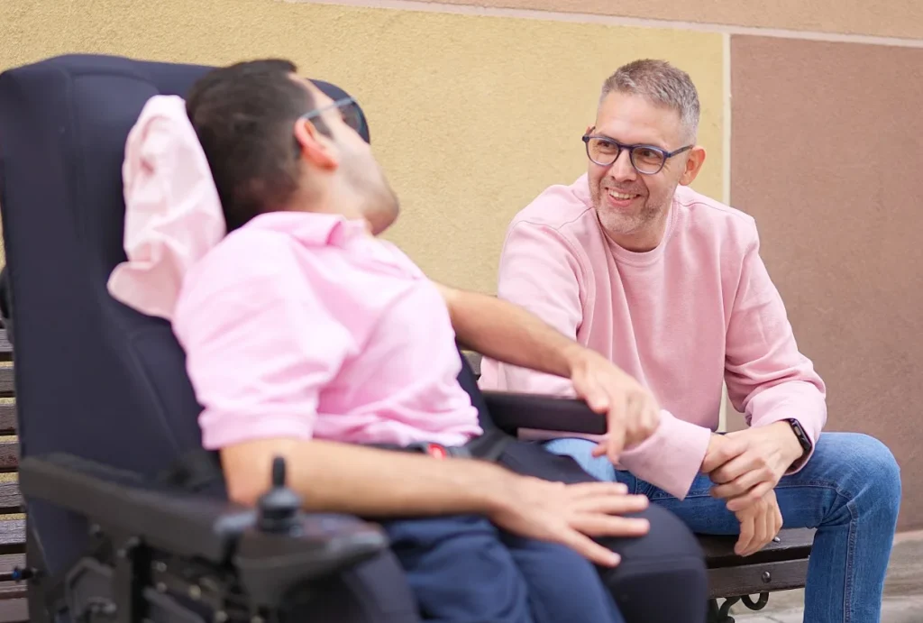 Carer chatting with client in wheelchair outdoors