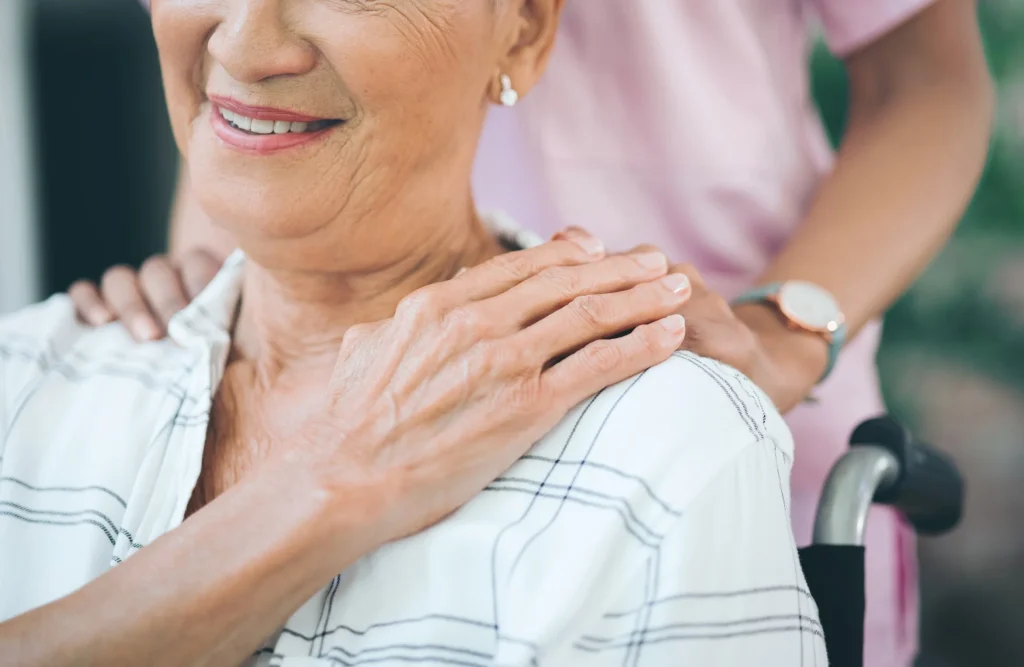 Caregiver comforting elderly woman in wheelchair